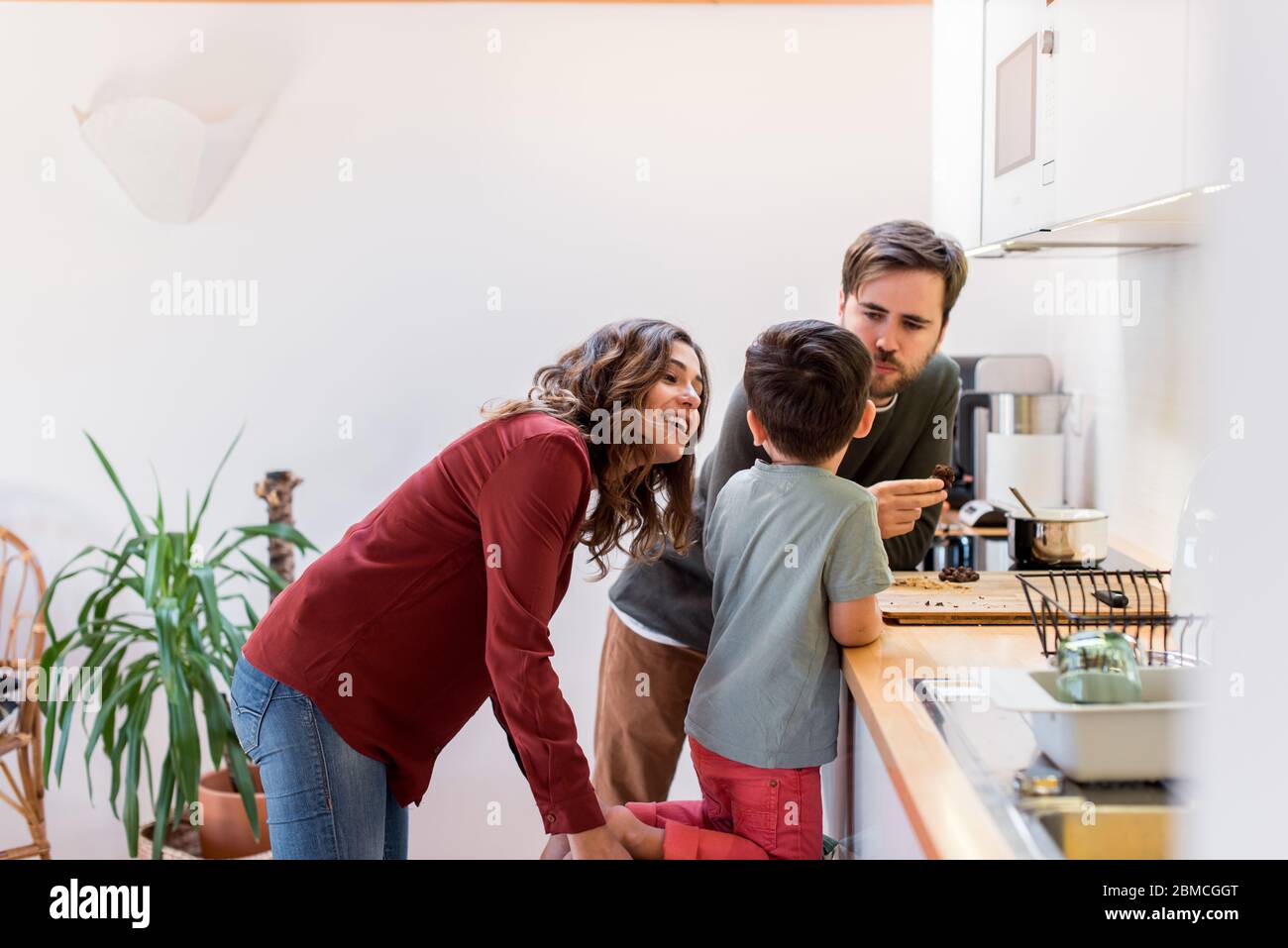 Family preparing and eating peanut chocolate cookies at home Stock Photo