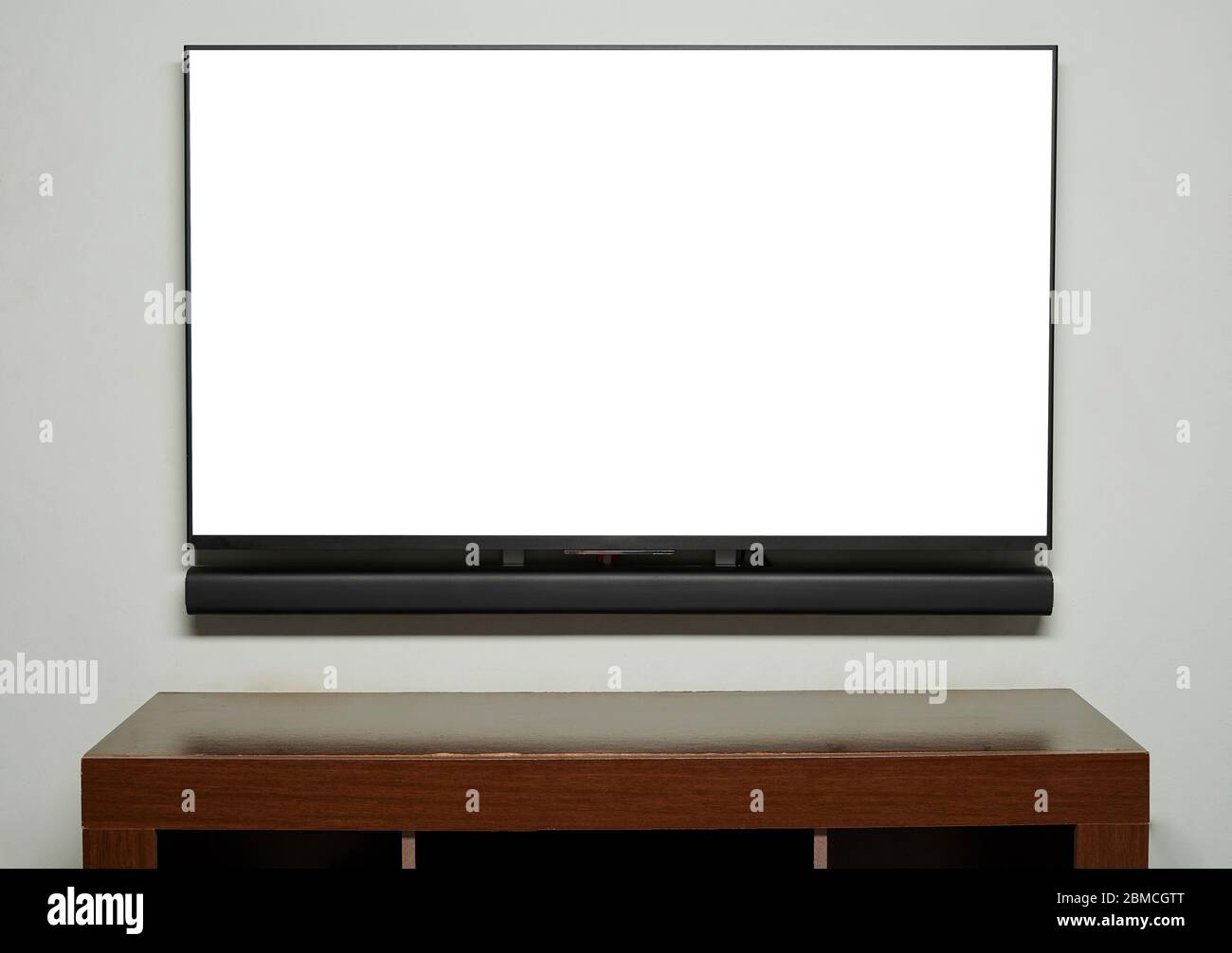 Big tv screen hang on wall with empty wooden table Stock Photo