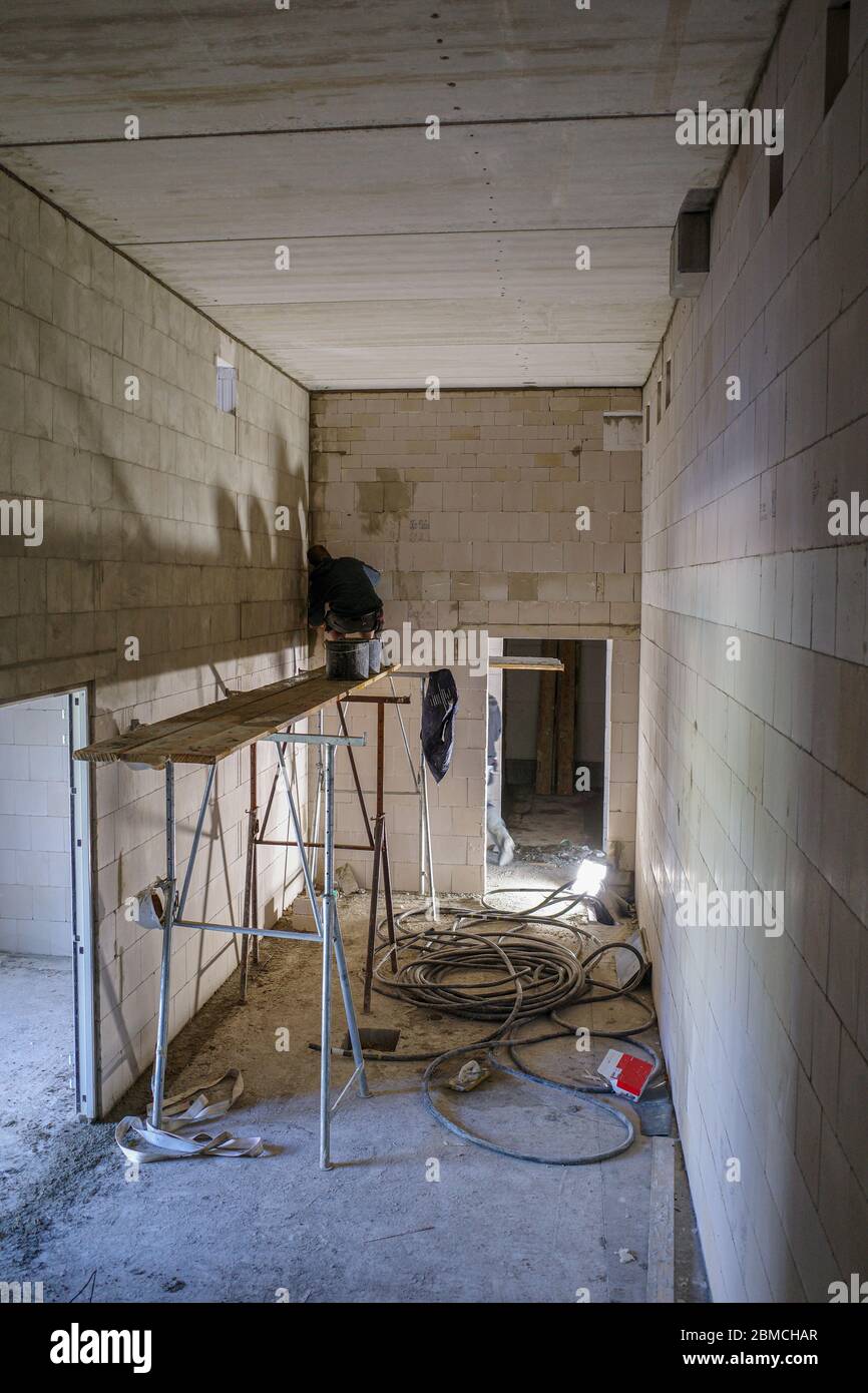 a mason works on a scaffold in a room without windows Stock Photo