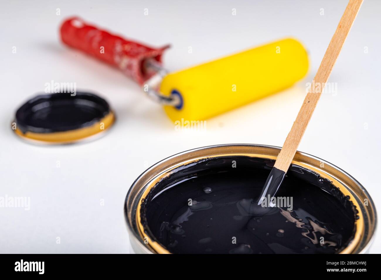 Black paint can and paint roller. Paint application accessories. Light background. Stock Photo
