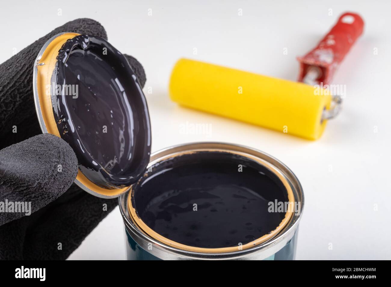 Black paint can and paint roller. Paint application accessories. Light background. Stock Photo