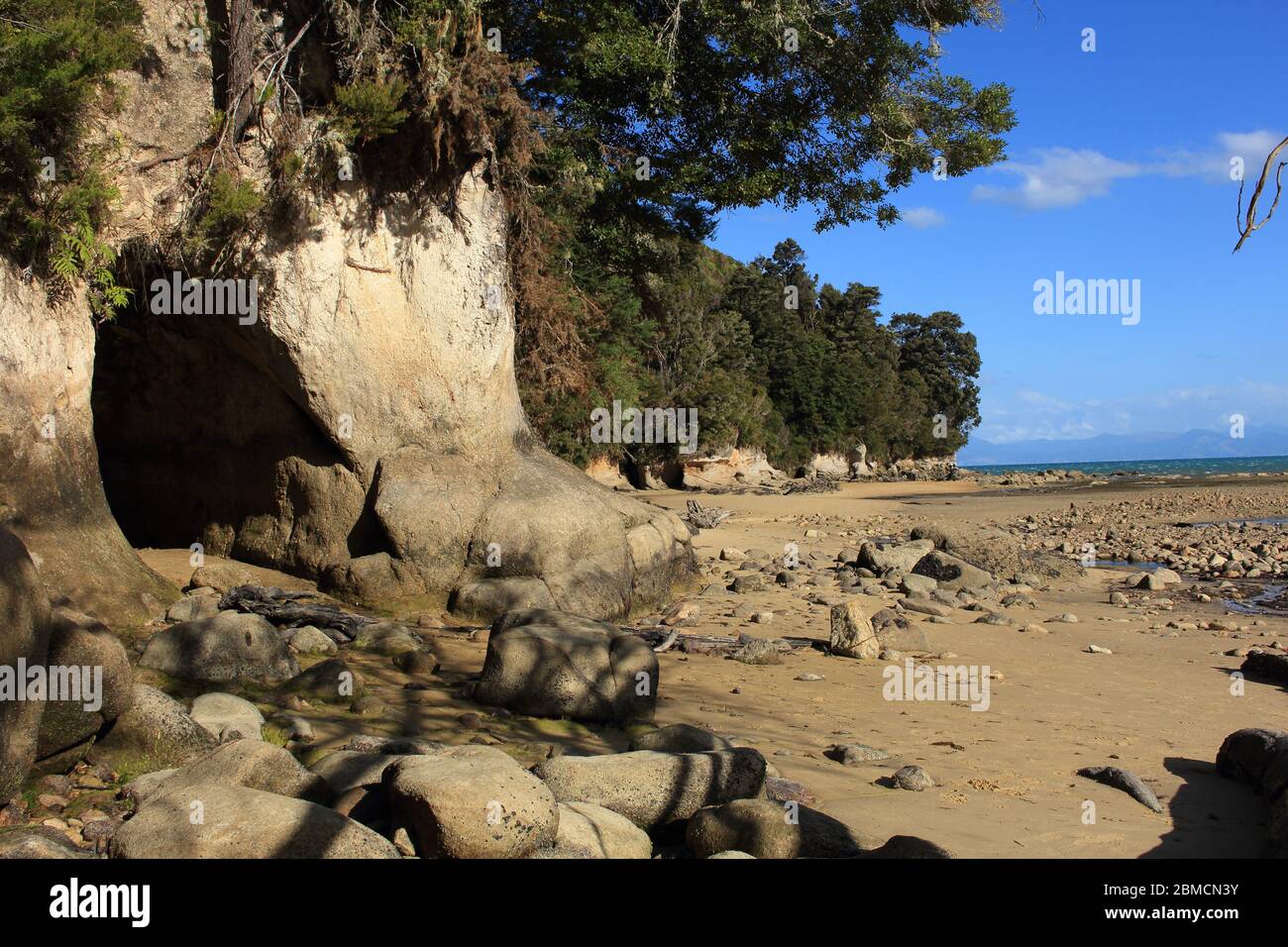 Robinson Crusoe Feeling at adventurous Beach with a cave at Tinline Bay in Abel Tasman National Park in New Zealand. In the background you see the oce Stock Photo