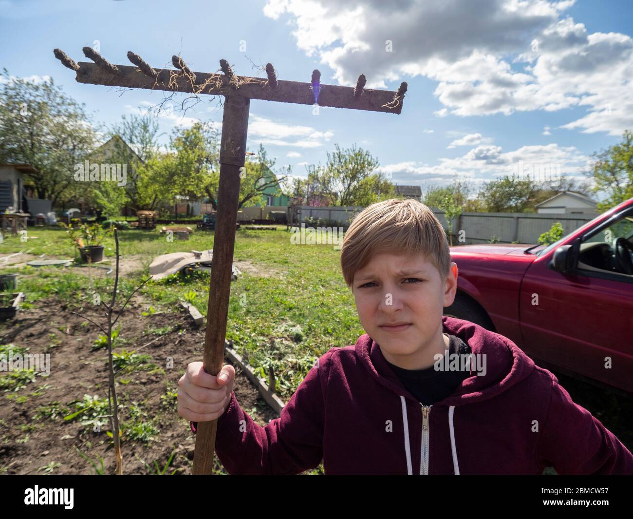 Caucasian boy posing with rake Stock Photo - Alamy