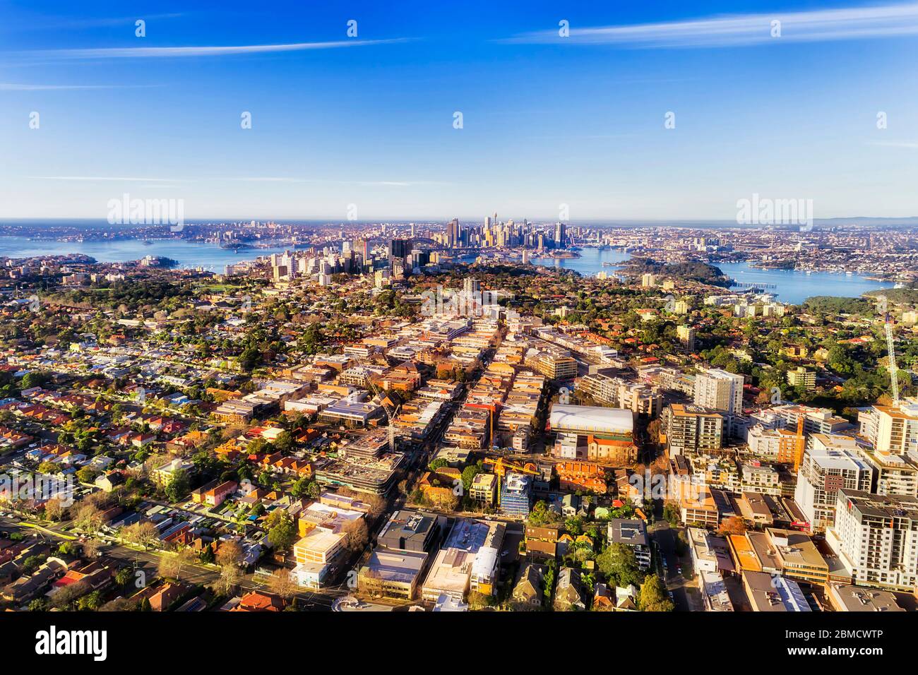 Lower north shore green leafy residential suburbs around Sydney harbour if elevated aerial view of city skyline under blue sky. Stock Photo