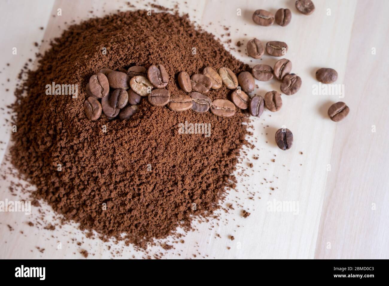 Top view of coffee beans and ground coffee on wooden background, roasted coffee volcano like anthill Stock Photo
