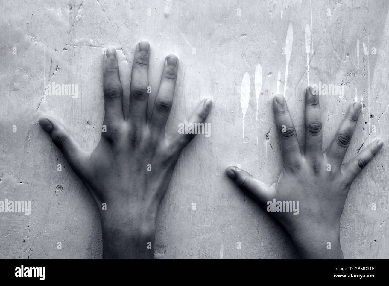 Two human hands one of male and another female over a blue colored background contrasting the size of two different individuals. Stock Photo