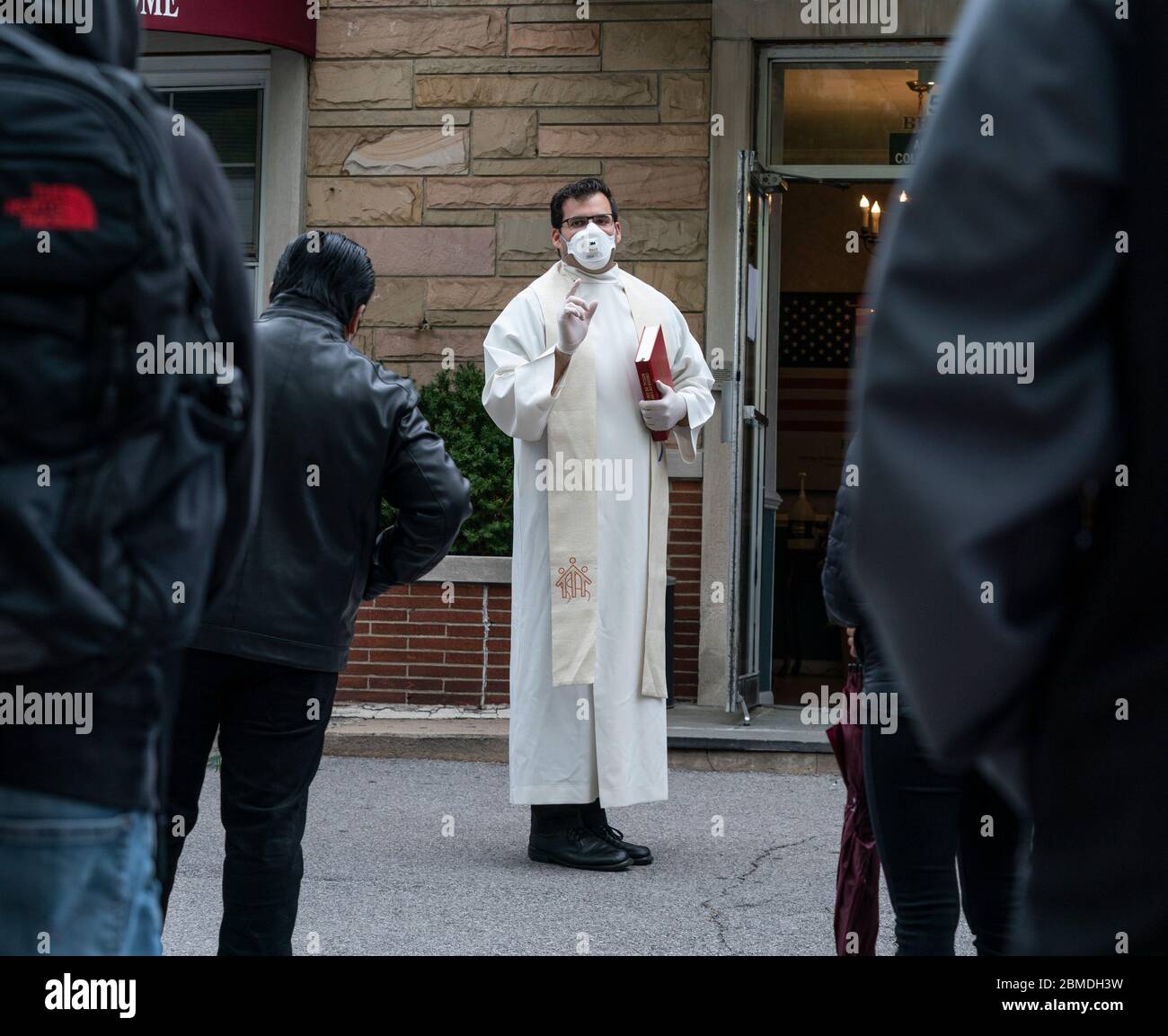 New York, NY May 8, 2020 Priest prays and reads portion of Bible at