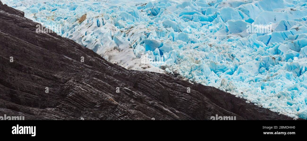 Volcanic rock and a blue ice glacier close up panorama, Grey Glacier, Patagonia, Chile. Stock Photo