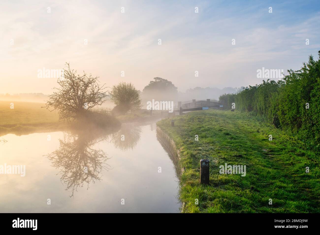 Lock and bridge in the mist on the Oxford canal on a spring morning just after sunrise. Upper Heyford, Oxfordshire, England Stock Photo