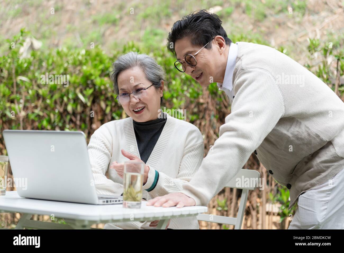 An Asian elderly couple is using a laptop Stock Photo