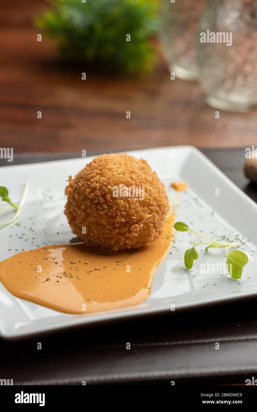 Arancini made with risotto and stuffed mozzarella on hot tomato sauce