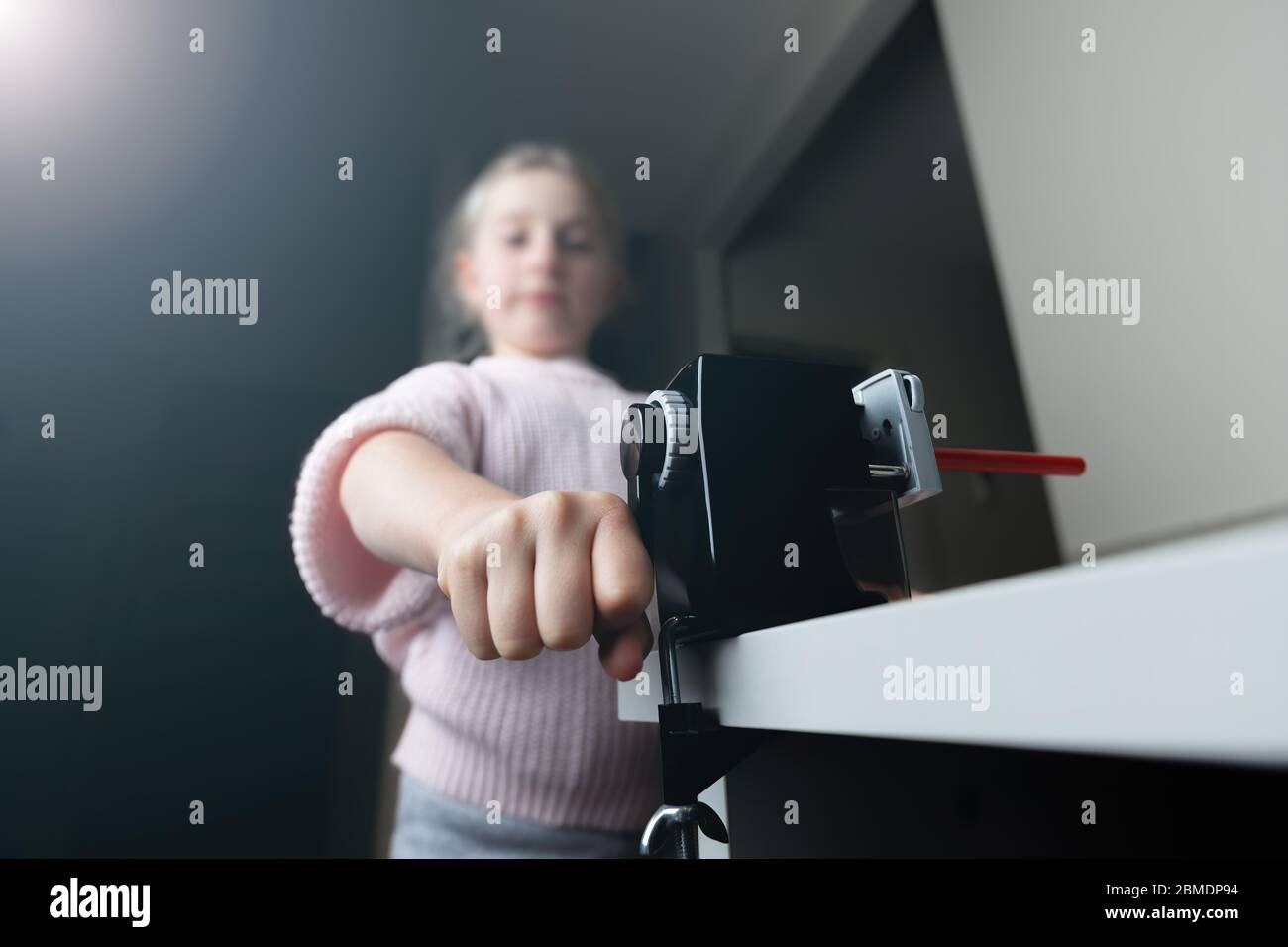 Girl sharpening a red pencil at home with shallow focus Stock Photo Alamy