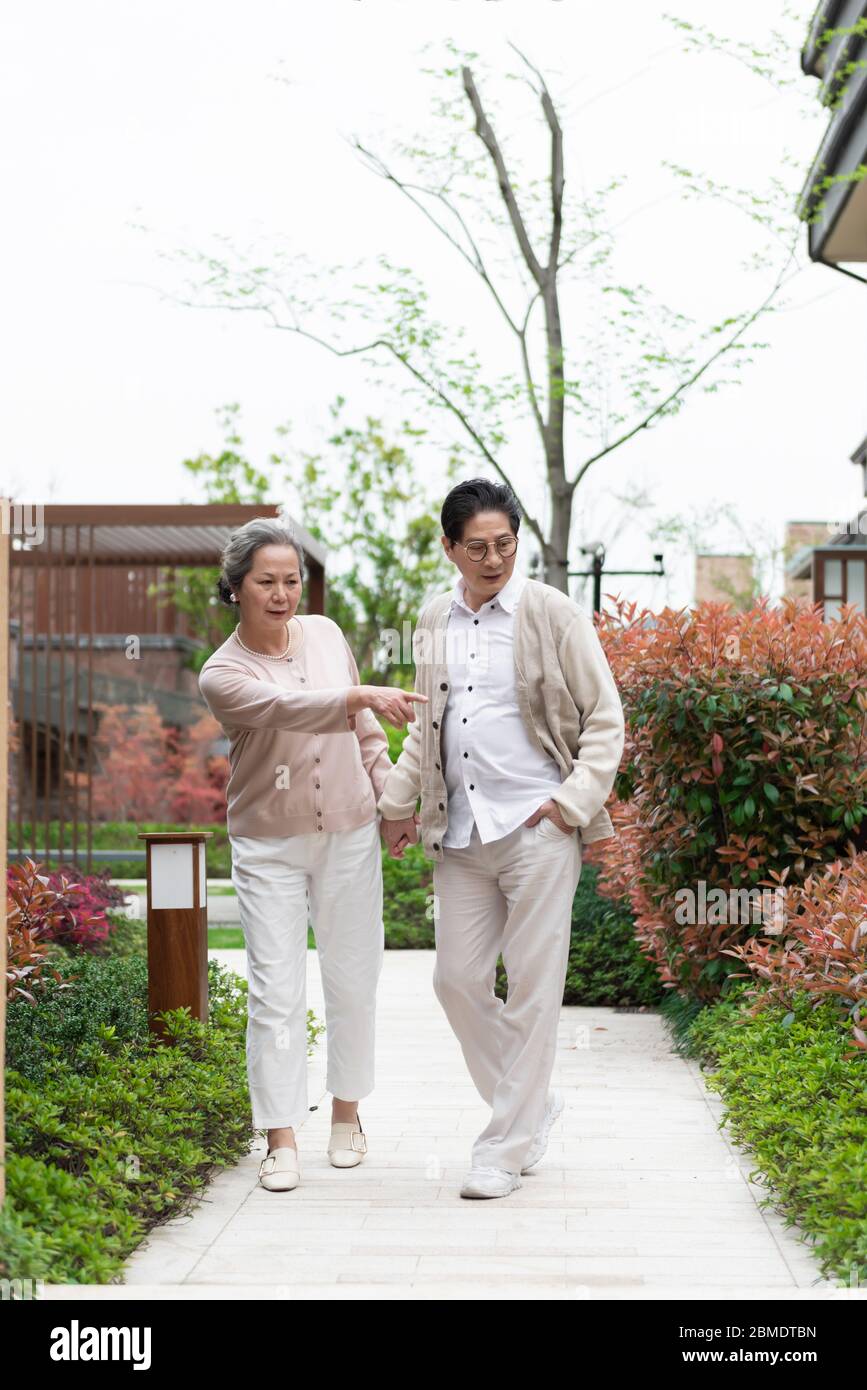 An Asian elderly couple walking in the community Stock Photo