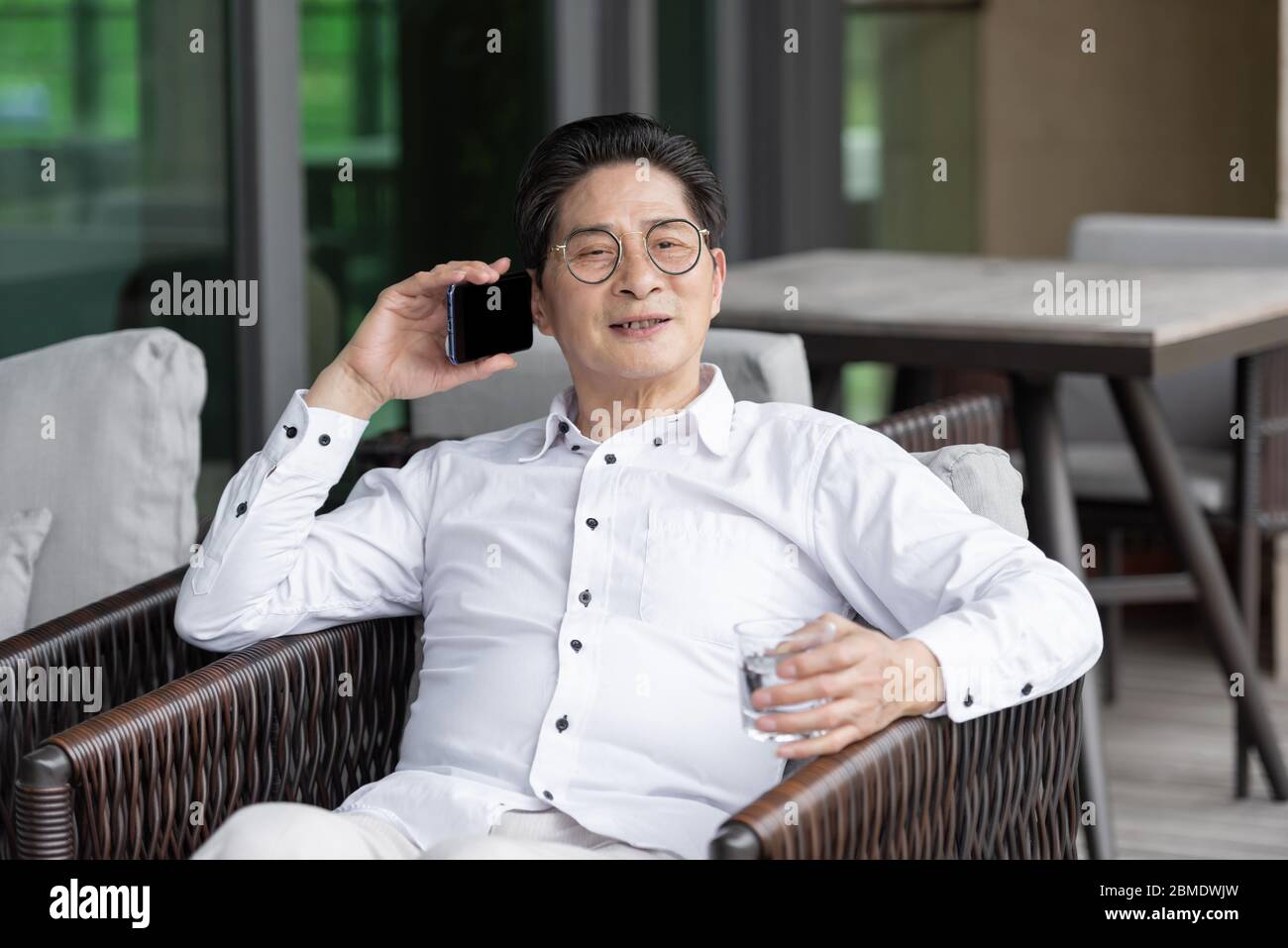 An Asian elderly man sitting on an outdoor chair Stock Photo - Alamy