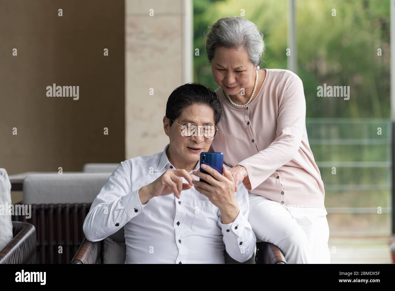 An Asian elderly couple sitting on an outdoor chair Stock Photo