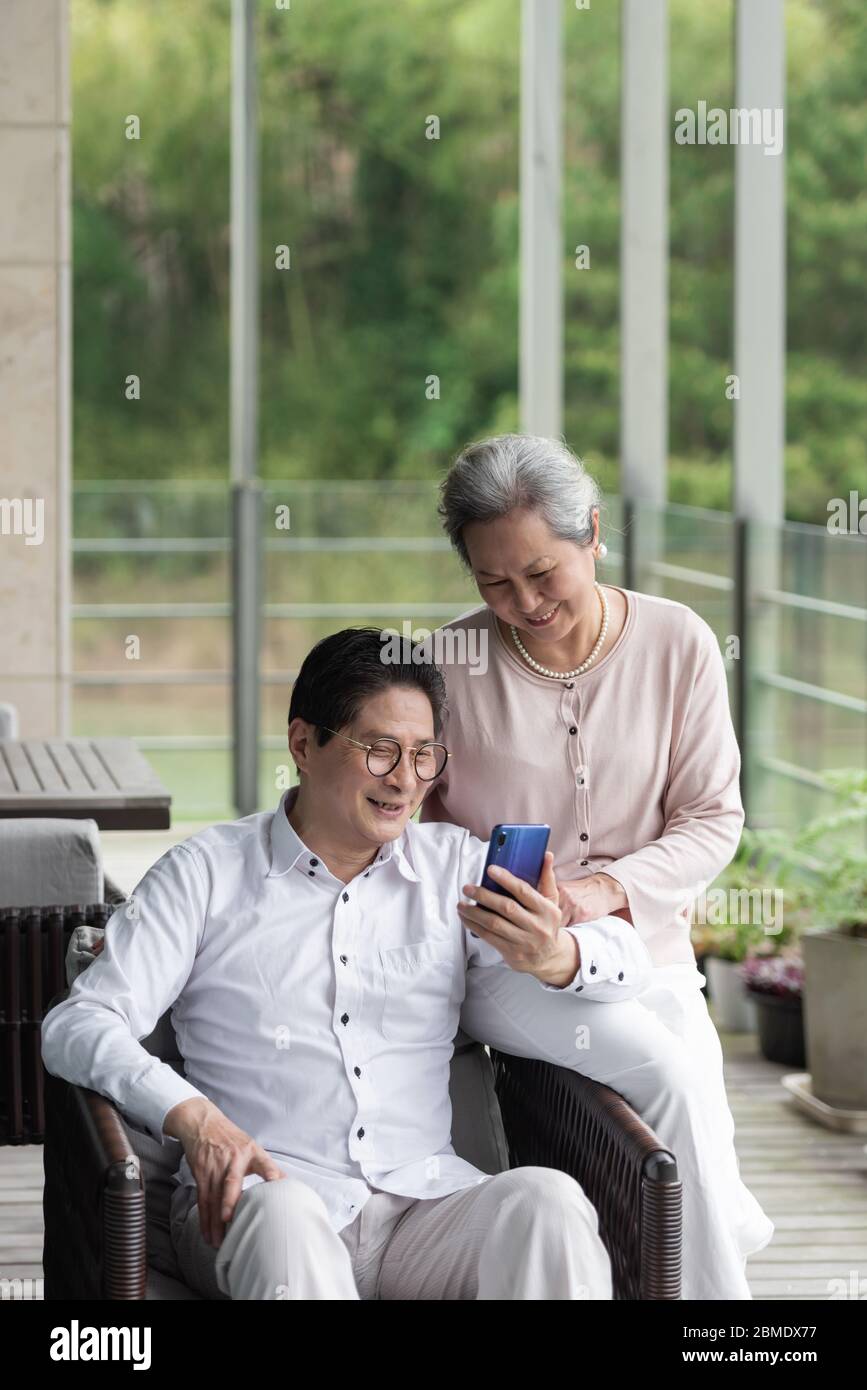 An Asian elderly couple sitting on an outdoor chair Stock Photo