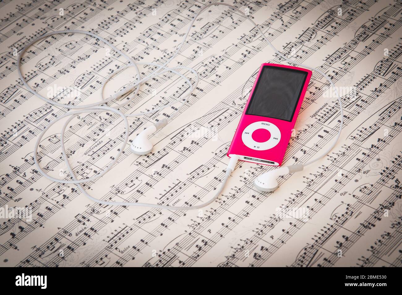Red Mp3 music player and earphones on a music sheet background with song  notes Stock Photo - Alamy