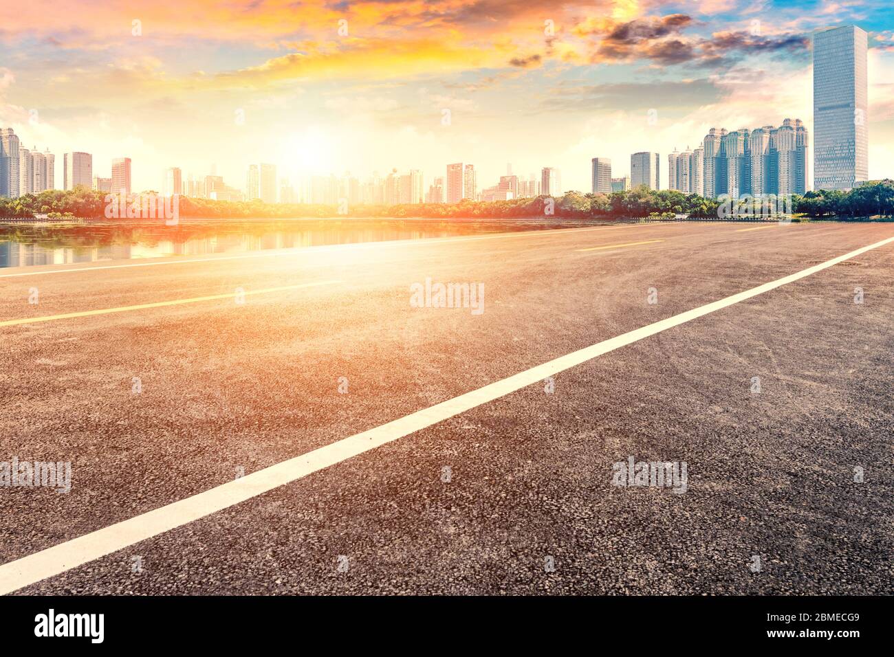Sunset landscape of empty asphalt road and city buildings. Stock Photo