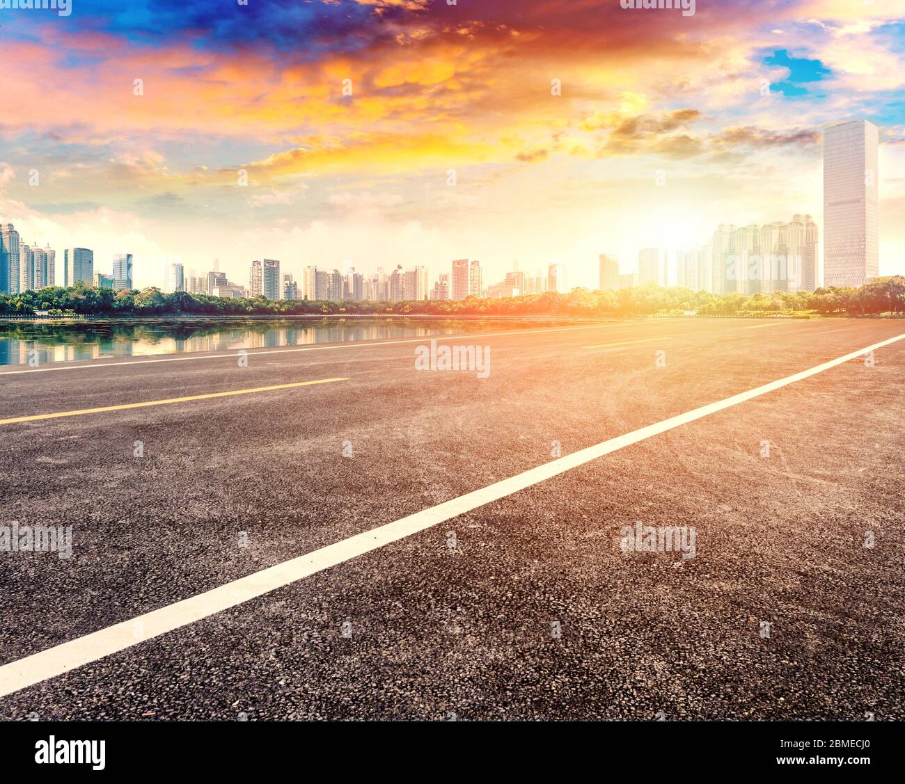 Sunset landscape of empty asphalt road and city buildings. Stock Photo