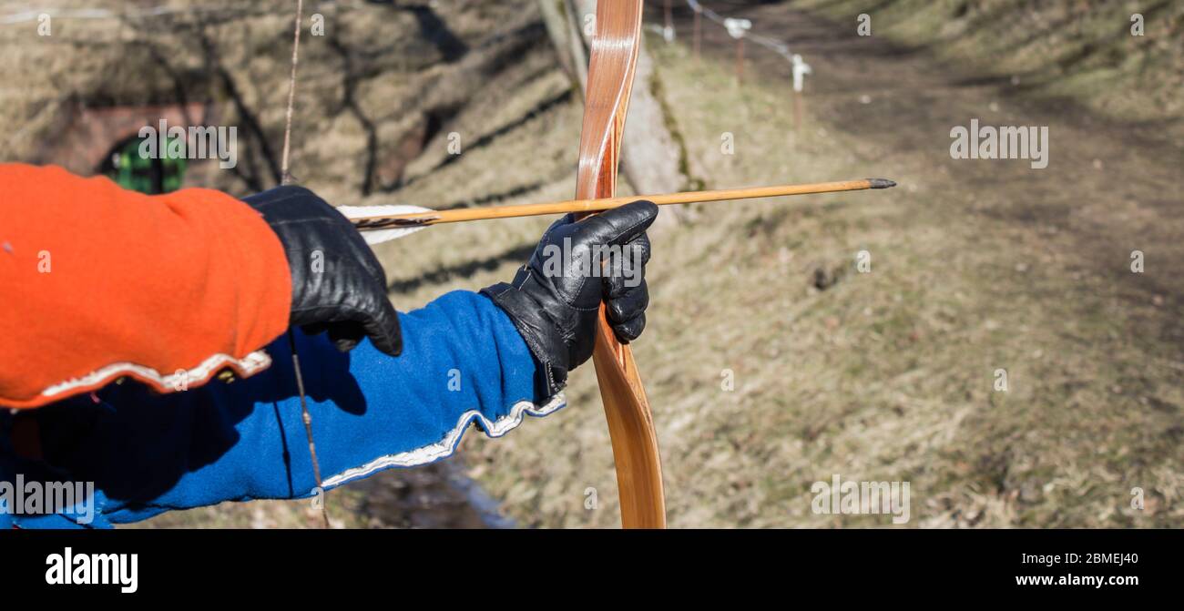 An archer with bow takes aim at a target during competition Stock Photo