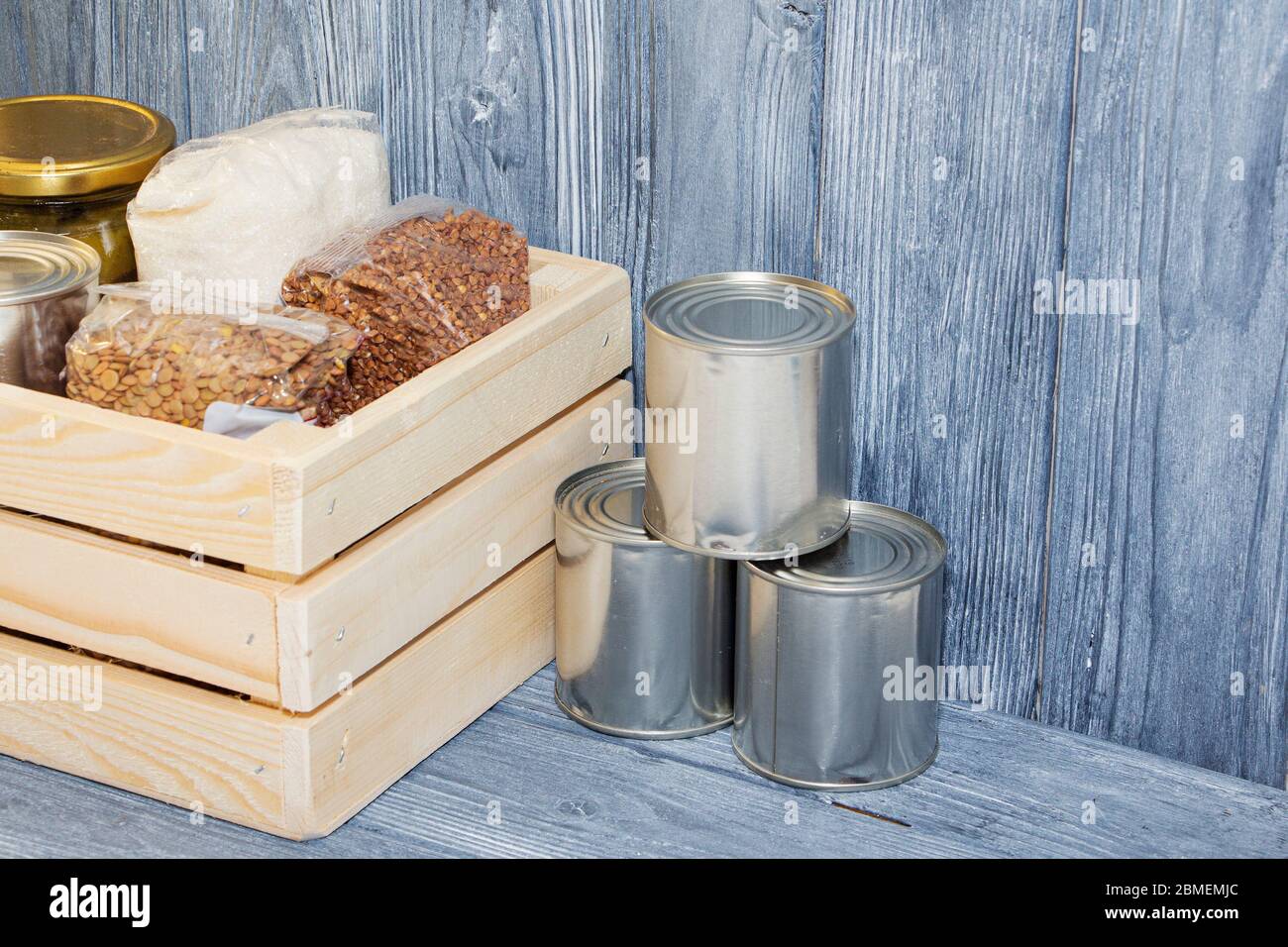 canned food and various cereals on a wooden shelf, food crisis. Stock Photo