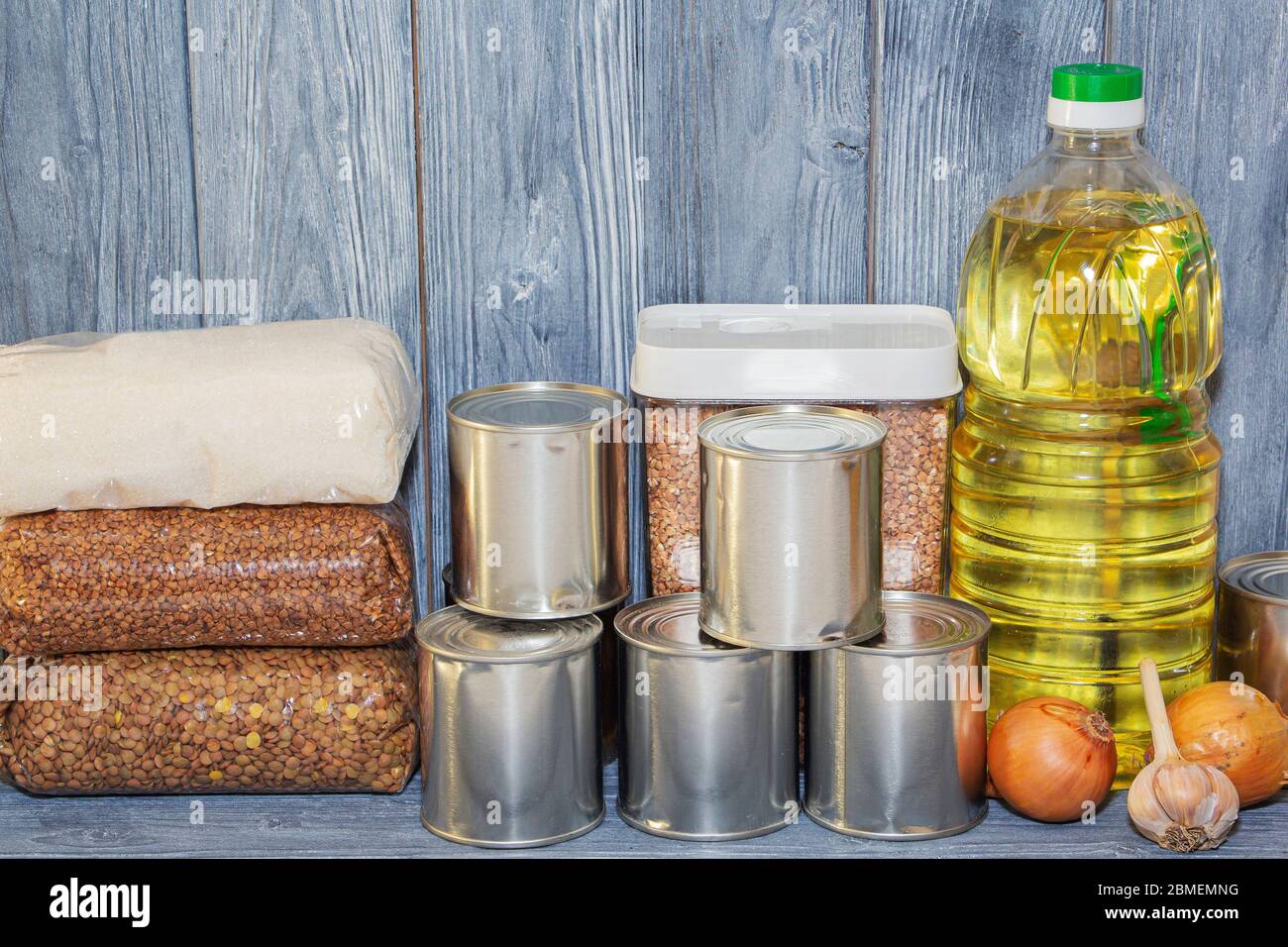 canned food and various cereals on a wooden shelf, food crisis. Stock Photo