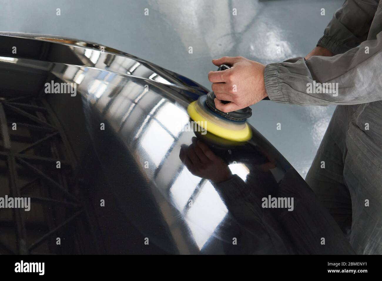Close-up of hands worker using polisher to polish a gray car body in the workshop, Auto Mechanic Polishing Car Stock Photo