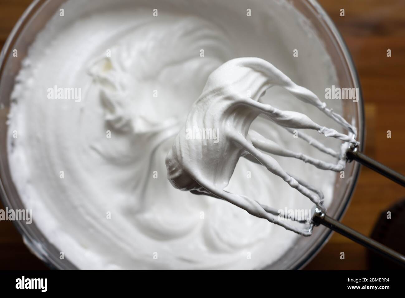 Electric mixer beaters above a soft mixed mergingue with the beaters still covered in the meringue Stock Photo