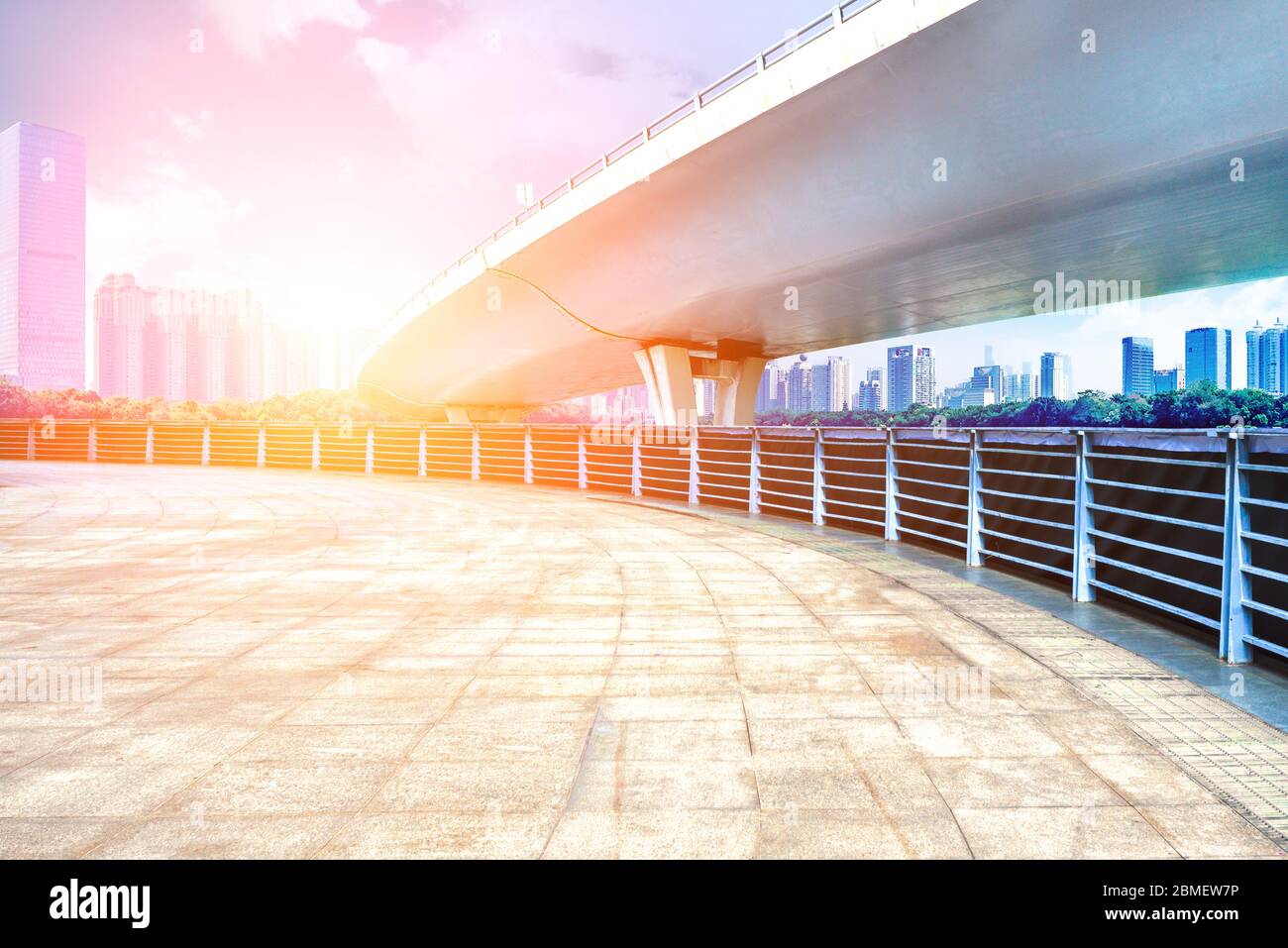 Under the overpass, car-free asphalt roads, modern city buildings as the background. Stock Photo