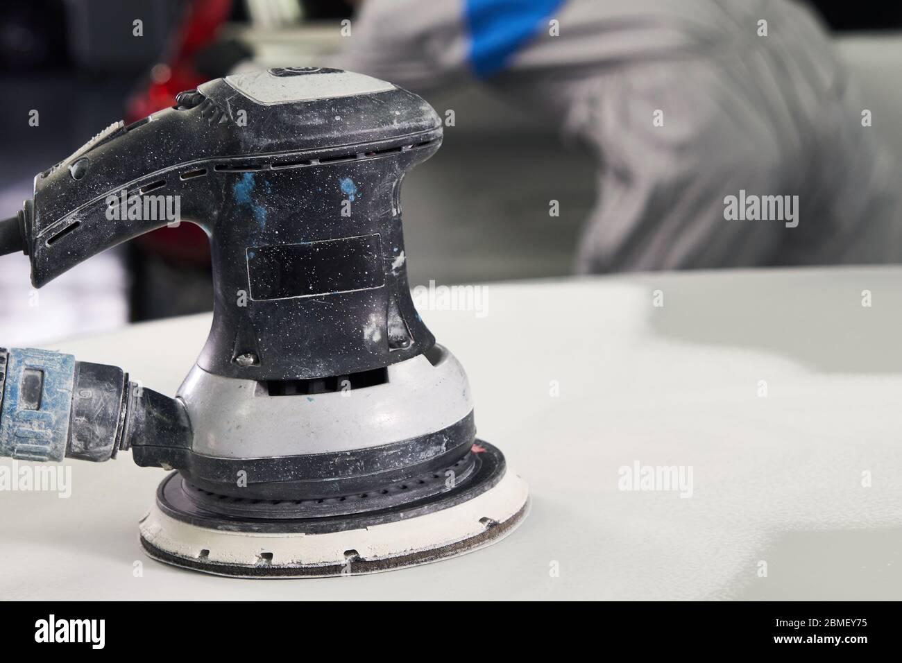 Auto mechanic buffing and polishing car in auto repair shop with