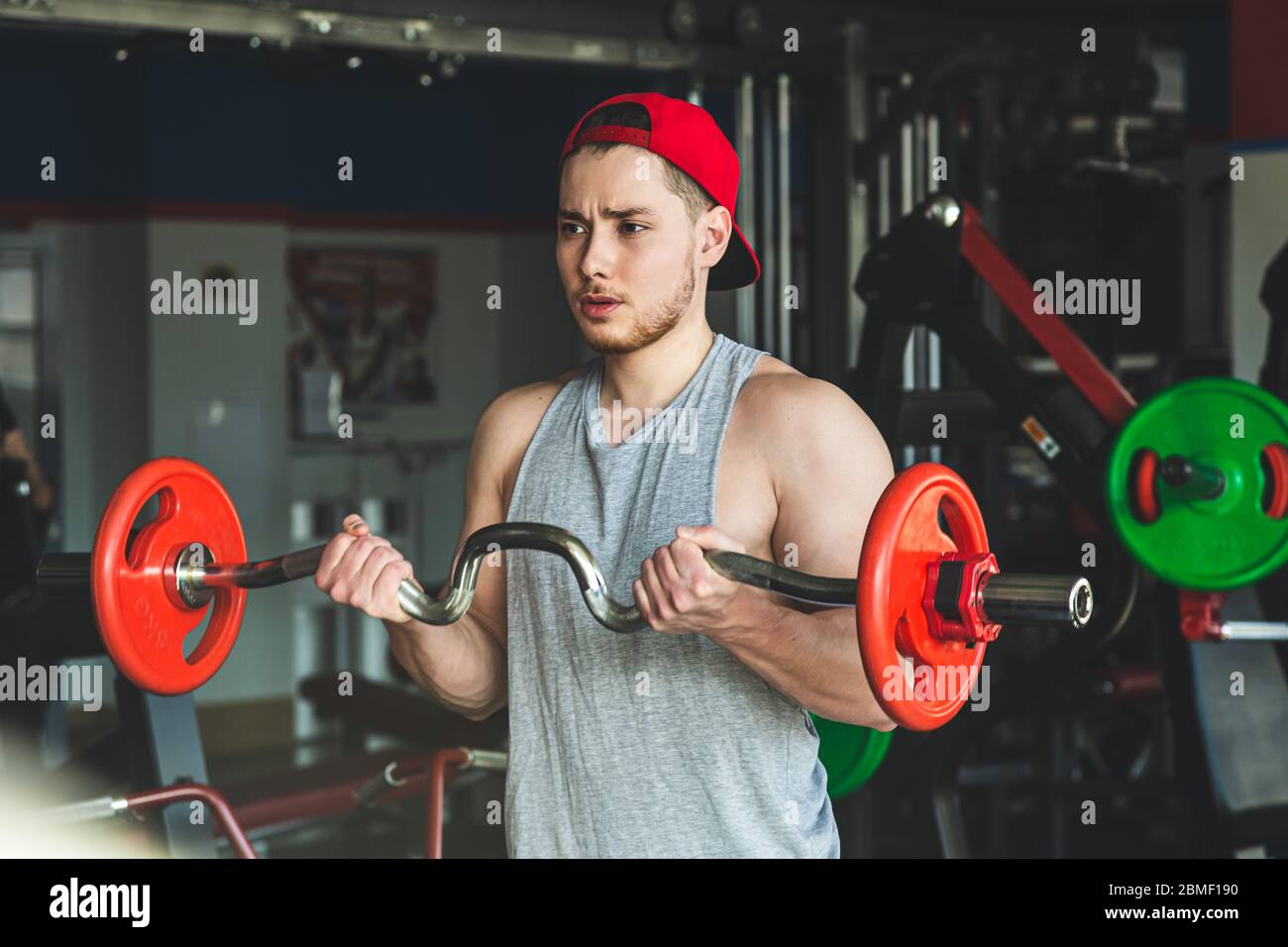 Portrait of a muscular young athlete performs exercises with a barbell