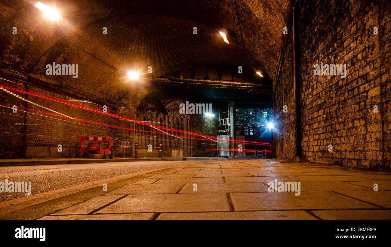 London, England, UK - November 28, 2013: Traffic leaves light trails at night on Crucifix Lane under the brick arch viaduct of London Bridge Railway S Stock Photo