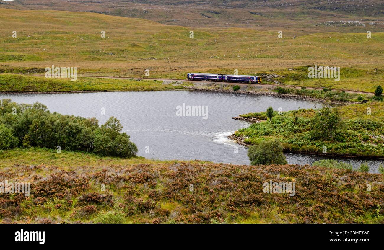 Inverness, Scotland, UK - September 25, 2013: A 2-car Scotrail passenger train travels along the Kyle Line railway beside a river in the remote Highla Stock Photo