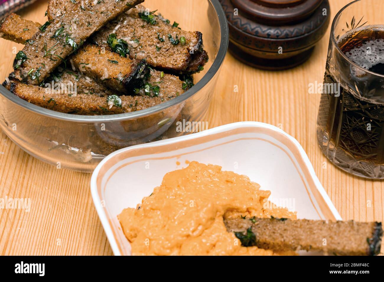 Beer snack fried croutons with cheese sauce on wooden board. Rye bread croutons with garlic, oil and salt. Drinks and food. Stock Photo