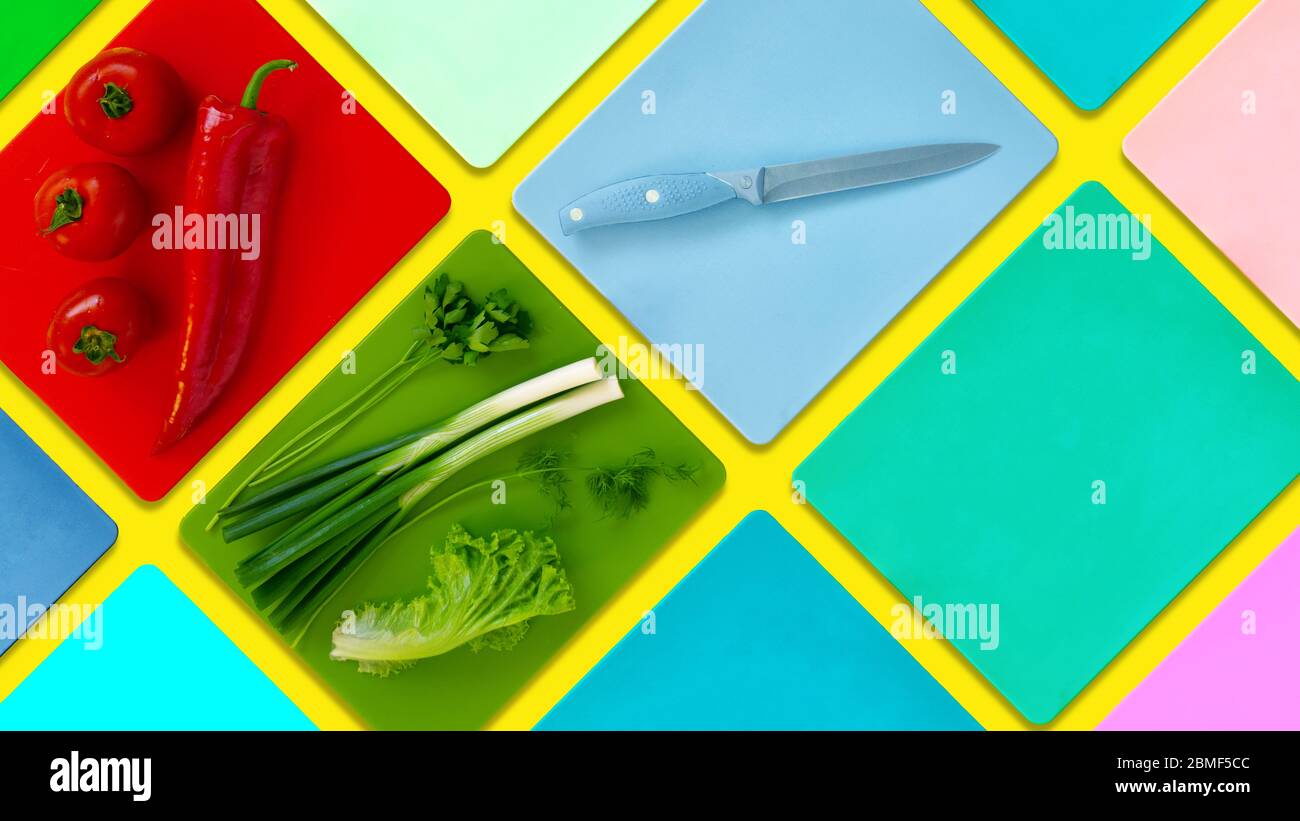 Flat lay of colored cutting boards with green fresh vegetable , fresh tomatoes and red bell pepper kapia colorful minimalist food copy space kitchen m Stock Photo