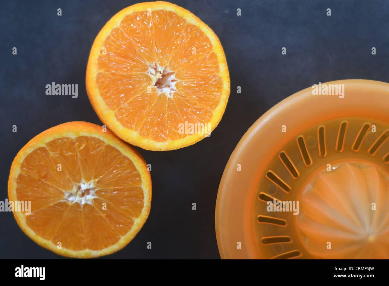 An orange cut in two halves and a squeezer Stock Photo
