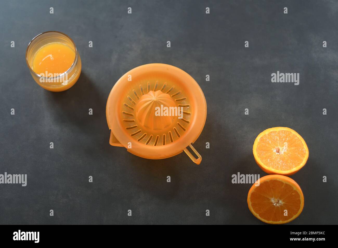 Oranges, squeezer and a glass of orange juice Stock Photo