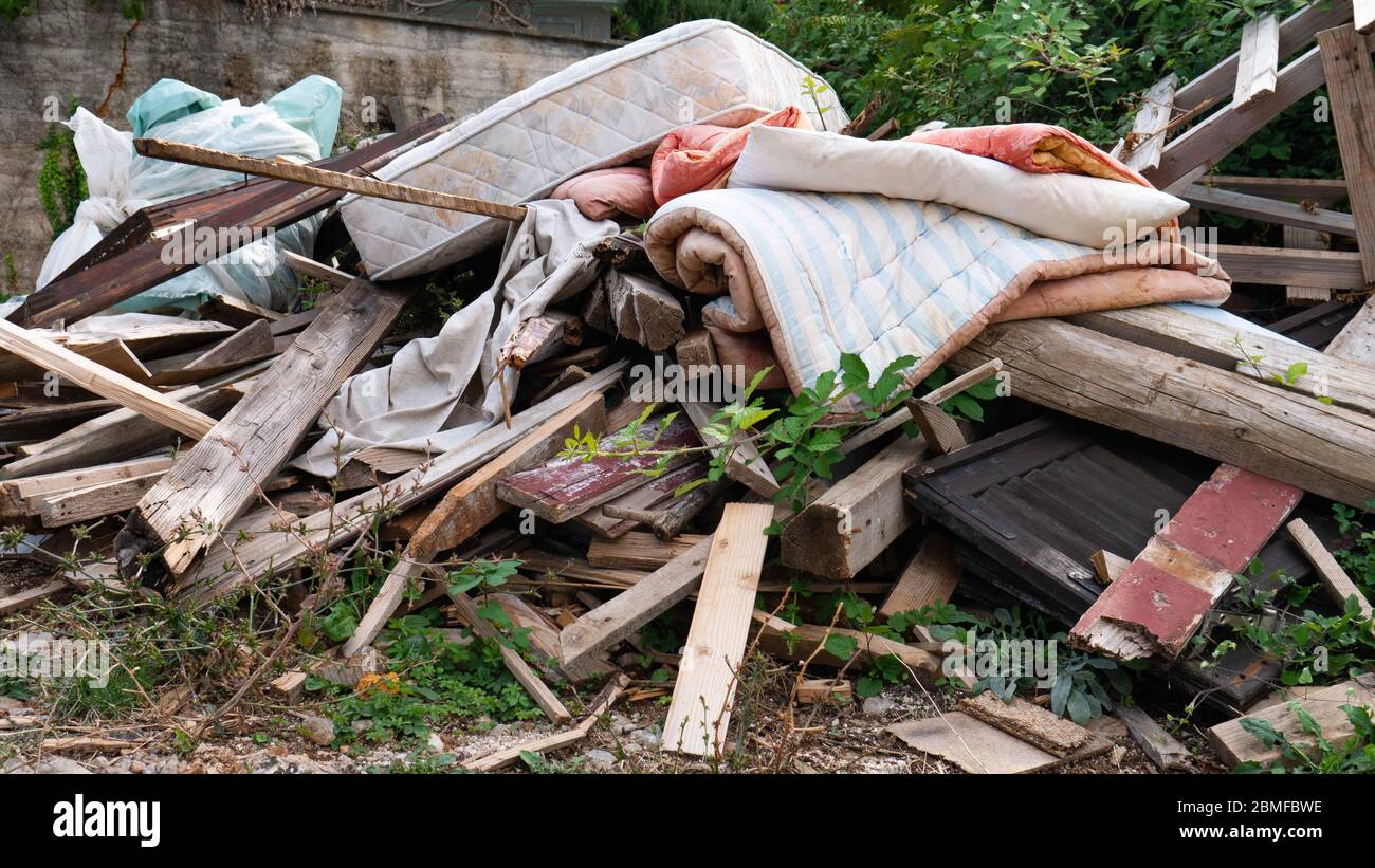 Garbage dumped boards, mattress, comforter, plastic bags full of