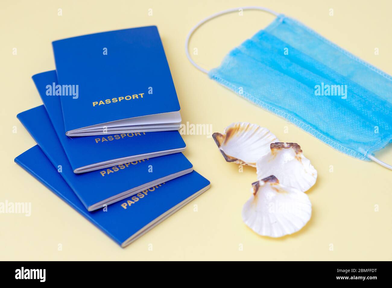 Travel concept during coronavirus. Travel concept with a four passports, medical mask and seashells on a blue and yellow background. Selective focus. Stock Photo