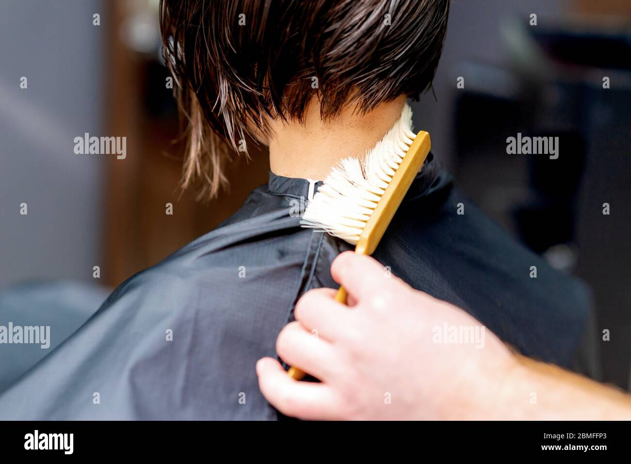 Hand os hairdresser is cleaning neck with brush from cutted hair after
