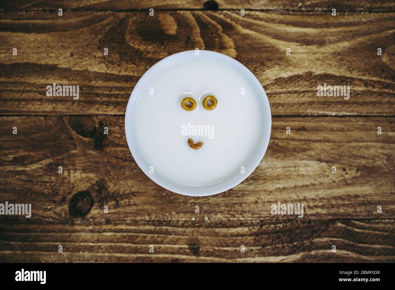 A bowl with just two and a half pieces of round cereal left creating the appearance of a face in the milk Stock Photo