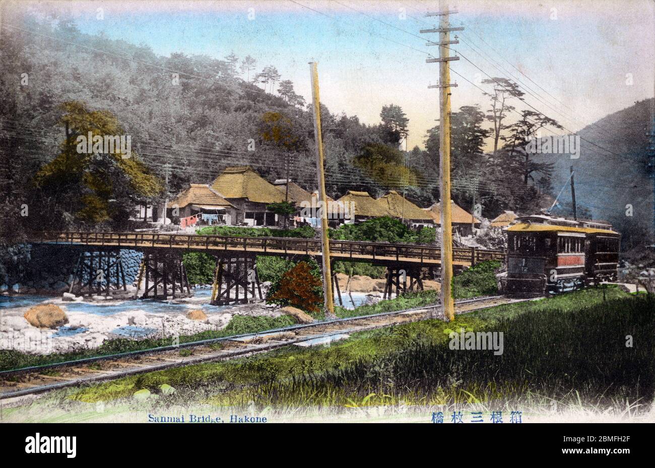 [ 1900s Japan - Train in Japanese Countryside ] —   A train rides along the Hayakawa River (早川) at Sanmaibashi (三枚橋) in Hakone, Kanagawa Prefecture. At the back, teahouses with thatched roofs are visible.  20th century vintage postcard. Stock Photo
