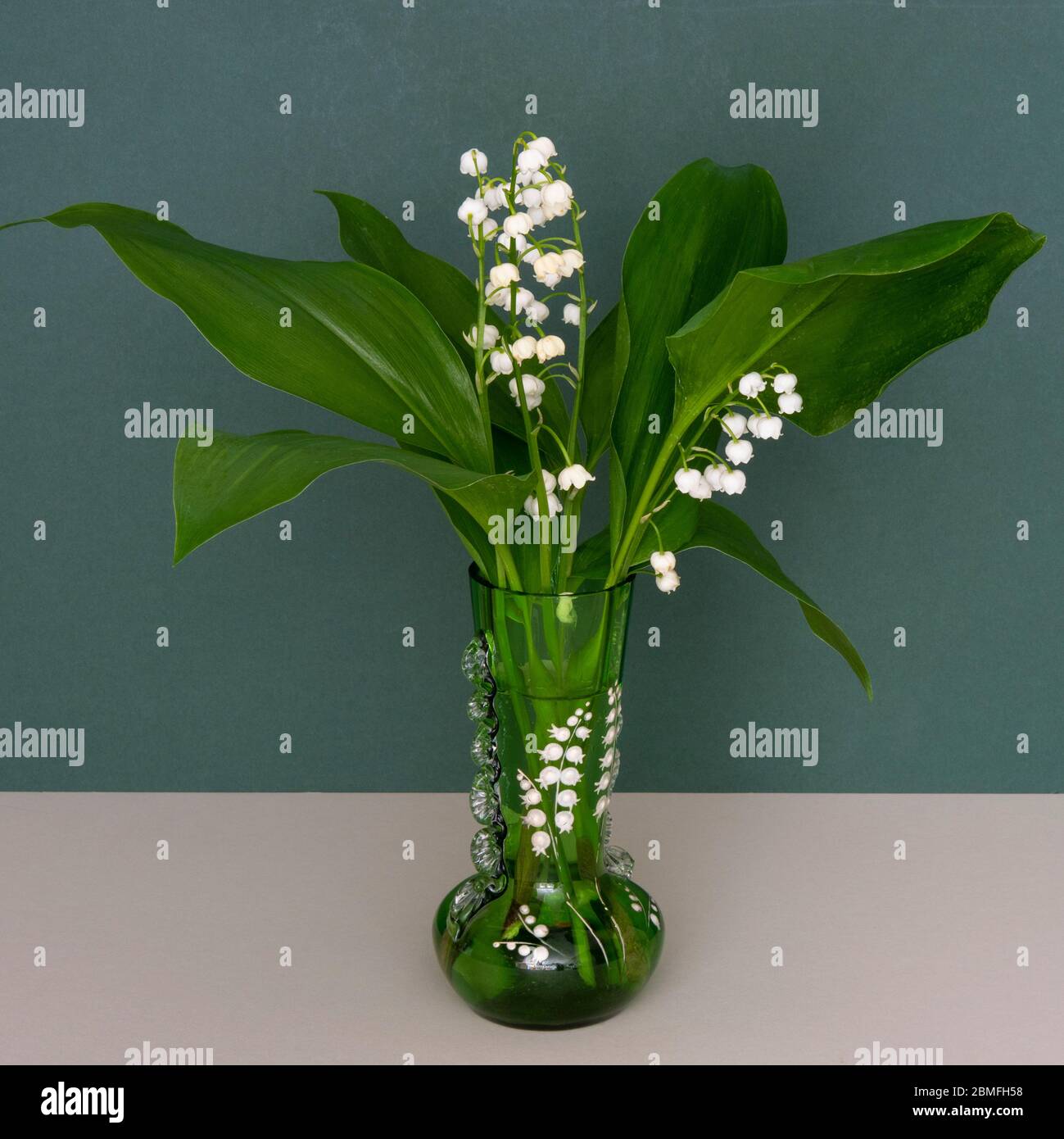 A Spring-time display of Lily of the valley flowers in a green Victorian vase Stock Photo