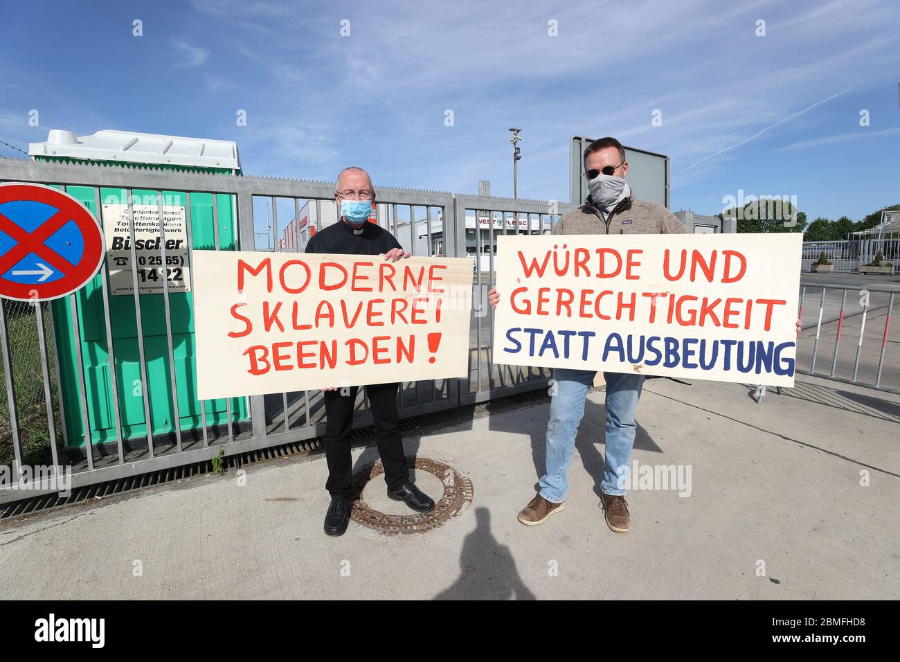 firo: 09.05.2020 General Corona Virus Kreis Coesfeld, Westfleisch, extension of the Corona restrictions Protest by two opponents of modern worker slavery before the closed factory in Coesfeld left: Private Peter Kossen and right with Dominik Blum (right) with posters 'Dignity and justice instead of exploitation' in front of the Westfleisch factory gate in Coesfeld They protest against unfair working conditions in the meat industry. He has been a pastor of the Seliger Niels Stensen parish in Lengerich since 2017. In 2018, he founded an association called 'Action Dignity and Justice' to help Bul Stock Photo