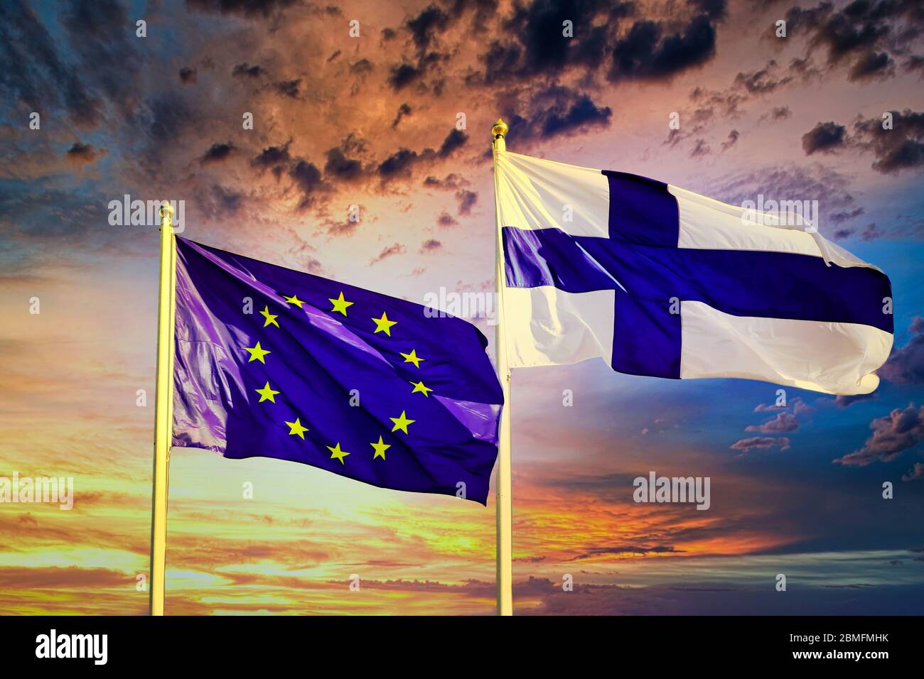 Flags of EU and Finland against colourful, dramatic sunset sky. Stock Photo