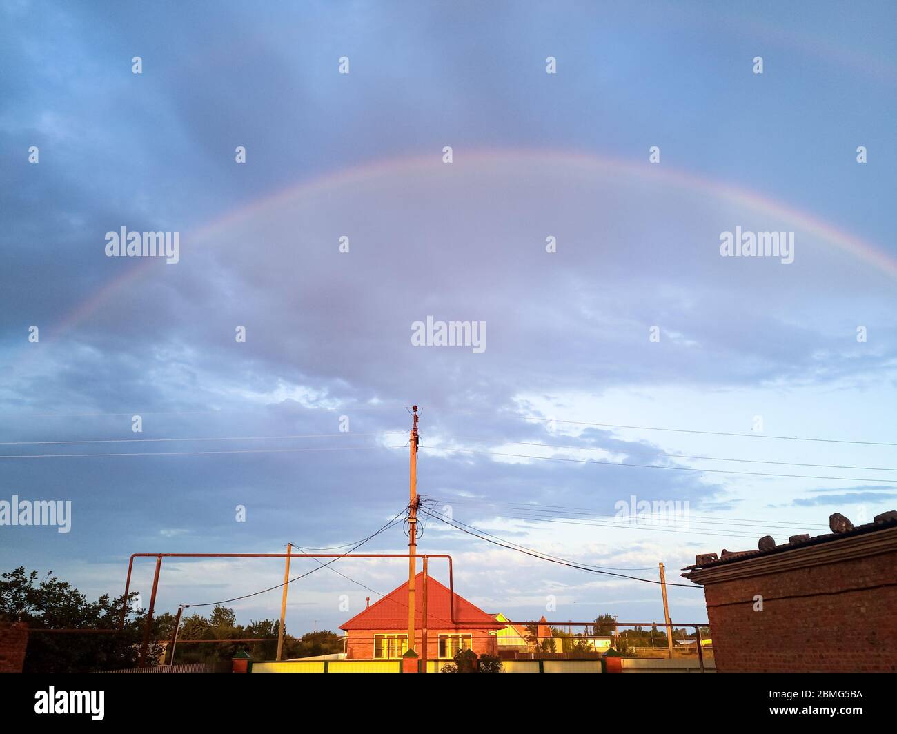 Rainbow over the village. Rainbow after rain. Stock Photo