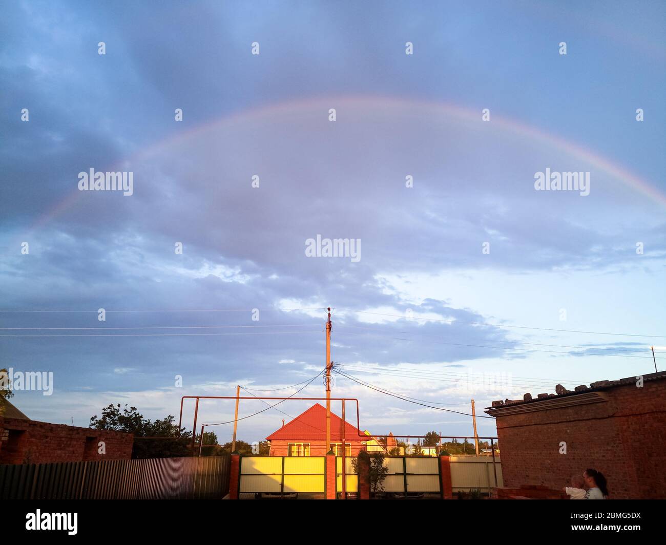 Rainbow over the village. Rainbow after rain. Stock Photo