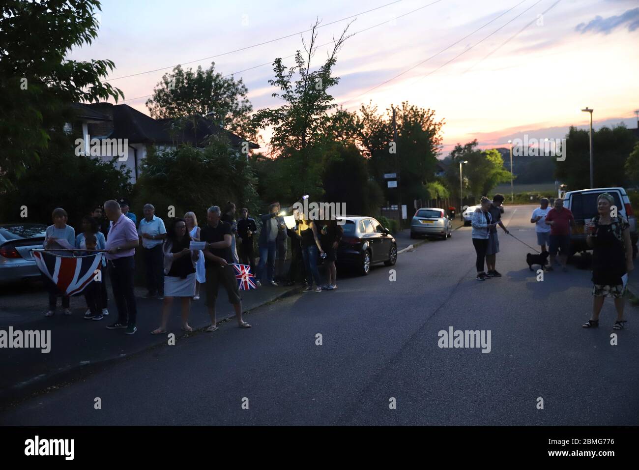 Hertfordshire, UK. 8th May 2020. Residents of Raglan Gardens, Oxhey Hall, gather during lockdown to listen to the Queen's Speech on big speakers followed by singing Dame Vera Lynn's We'll Meet Again and God Save The Queen. The residents of the whole street gathered around No12 who had organised the event to mark the 75th Anniversary of VE Day 8th May 2020 Credit: Ayeesha Walsh/Alamy Live News Stock Photo