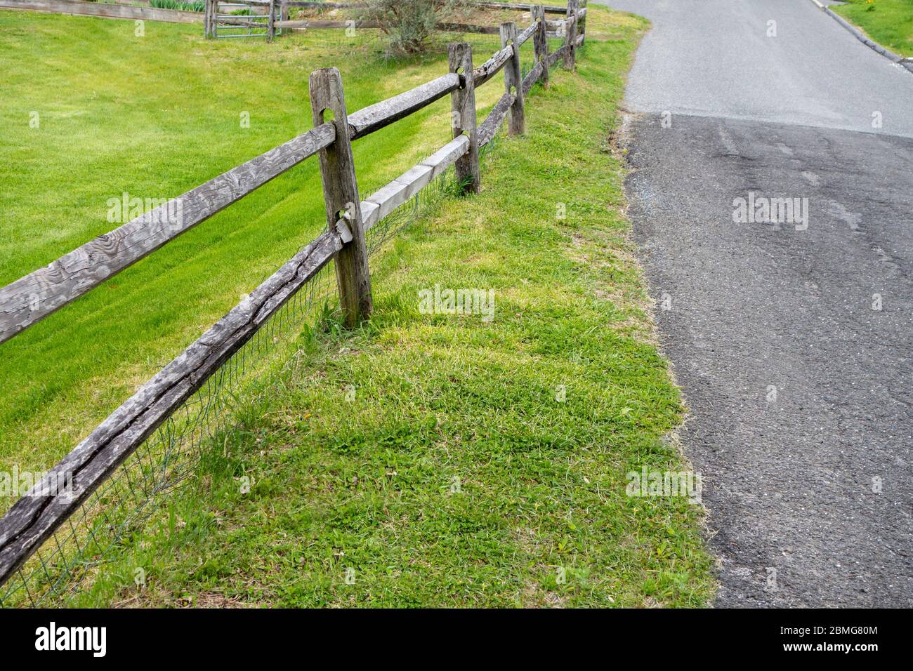 road pathway with 2 Rail Post wood fence along green grass lawn Stock ...