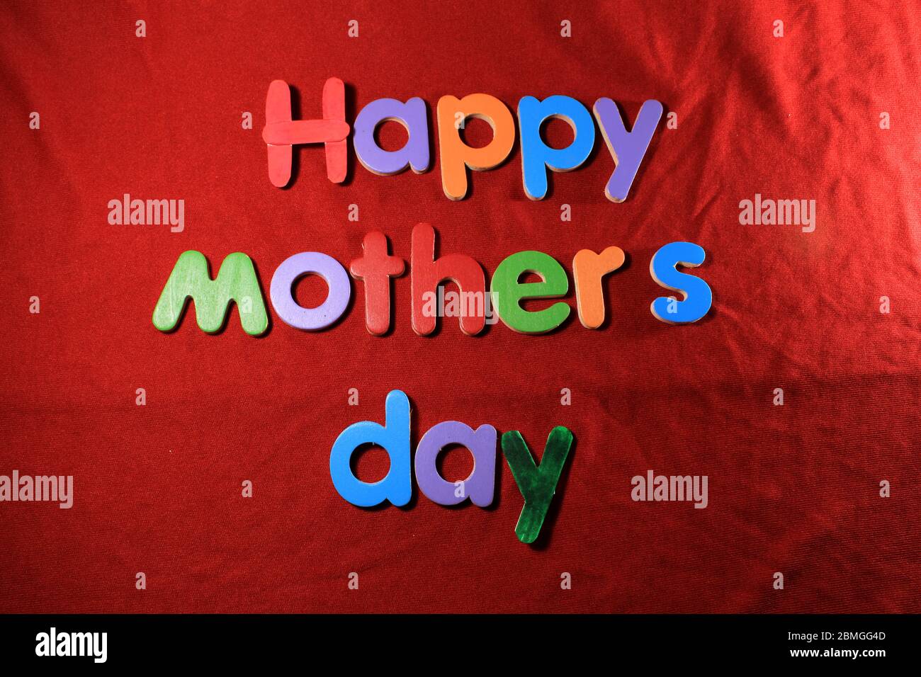 Happy Mother's Day written on red cloth texture background. Happy Mother's day written by colorful alphabet blocks. Stock Photo